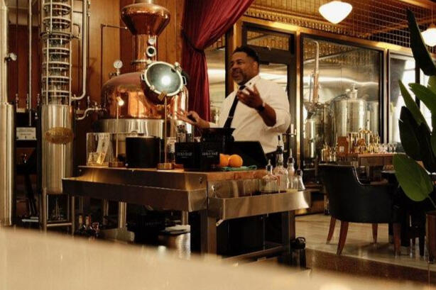 Hospitality professional presenting near copper distillation equipment during a spirits education experience